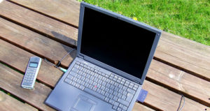 An image of a laptop and wireless phone on a picnic table